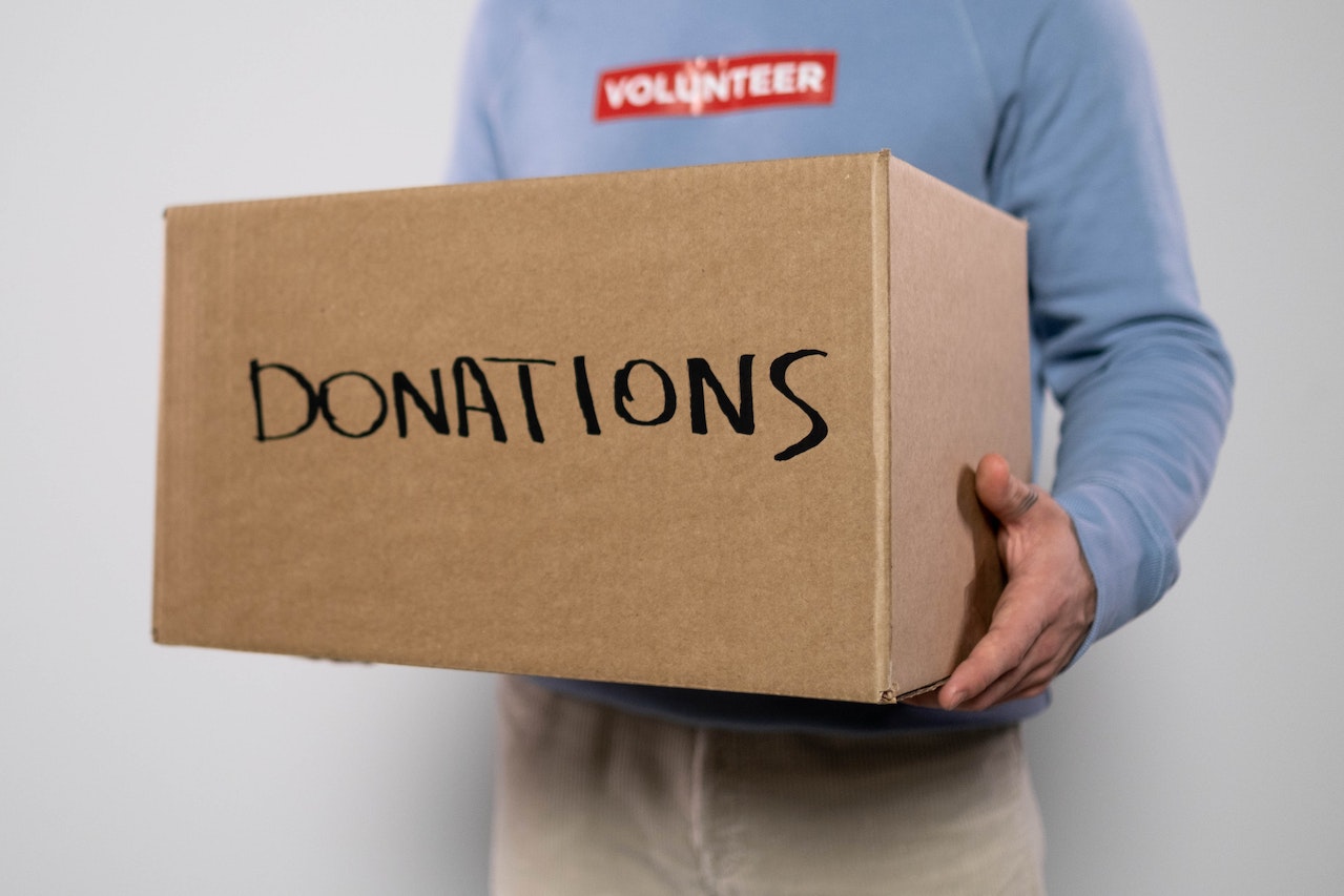 A Volunteer Carrying a Box of Donations | Veteran Car Donations
