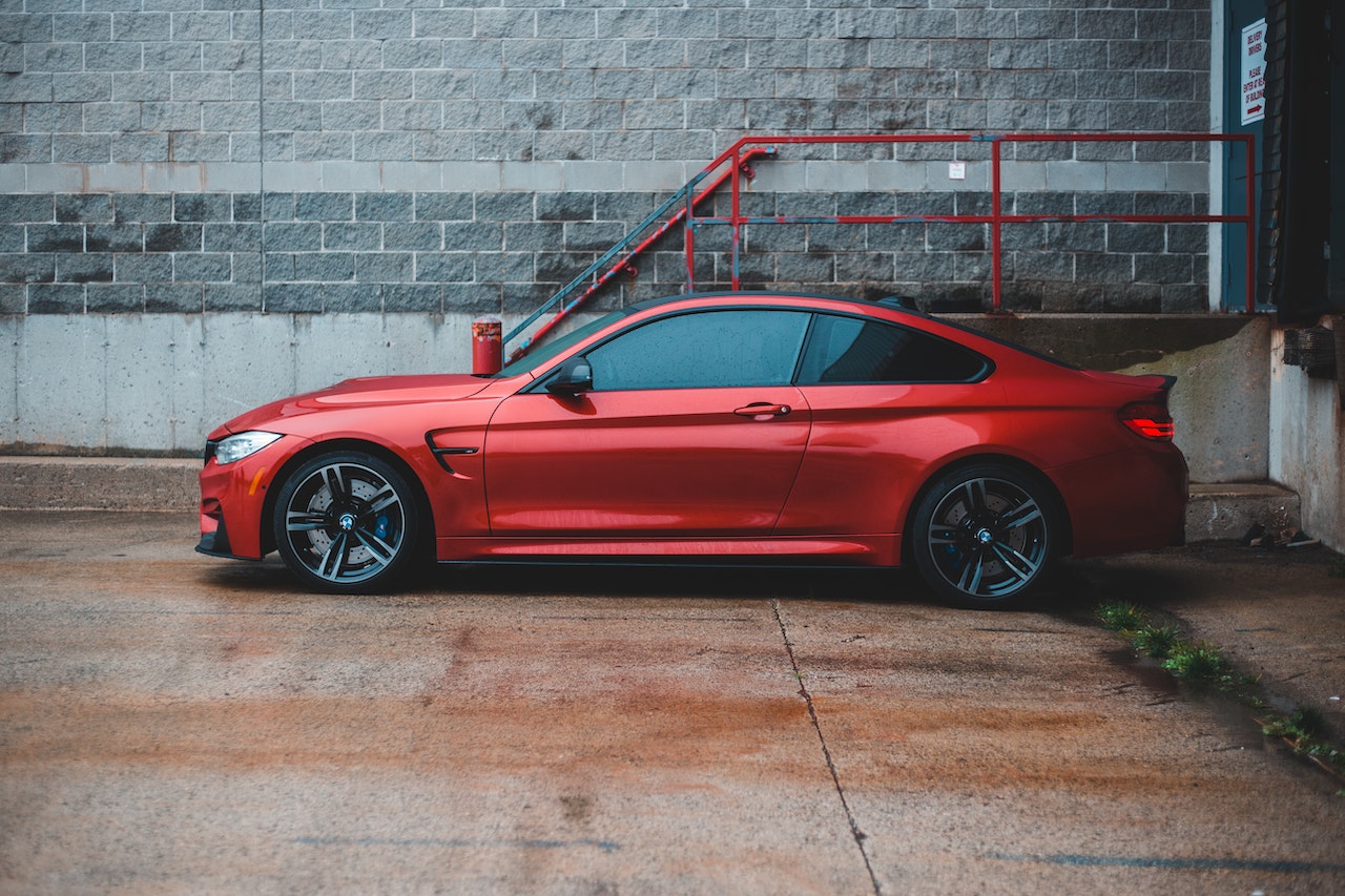 Red coupe car parked near shabby building | Veteran Car Donations