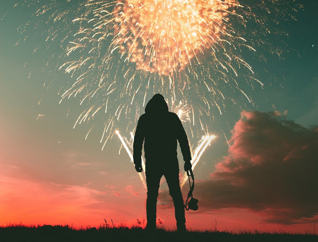 Silhouette Photo of Standing Man Holding Camera Looking at Fireworks Display | Veteran Car Donations
