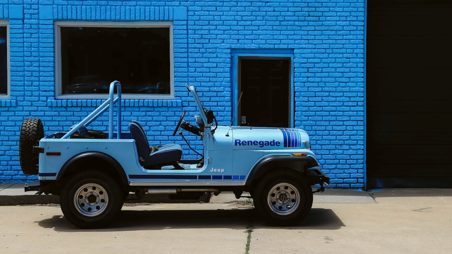 White and Black Jeep wrangler parked beside blue building | Veteran Car Donations