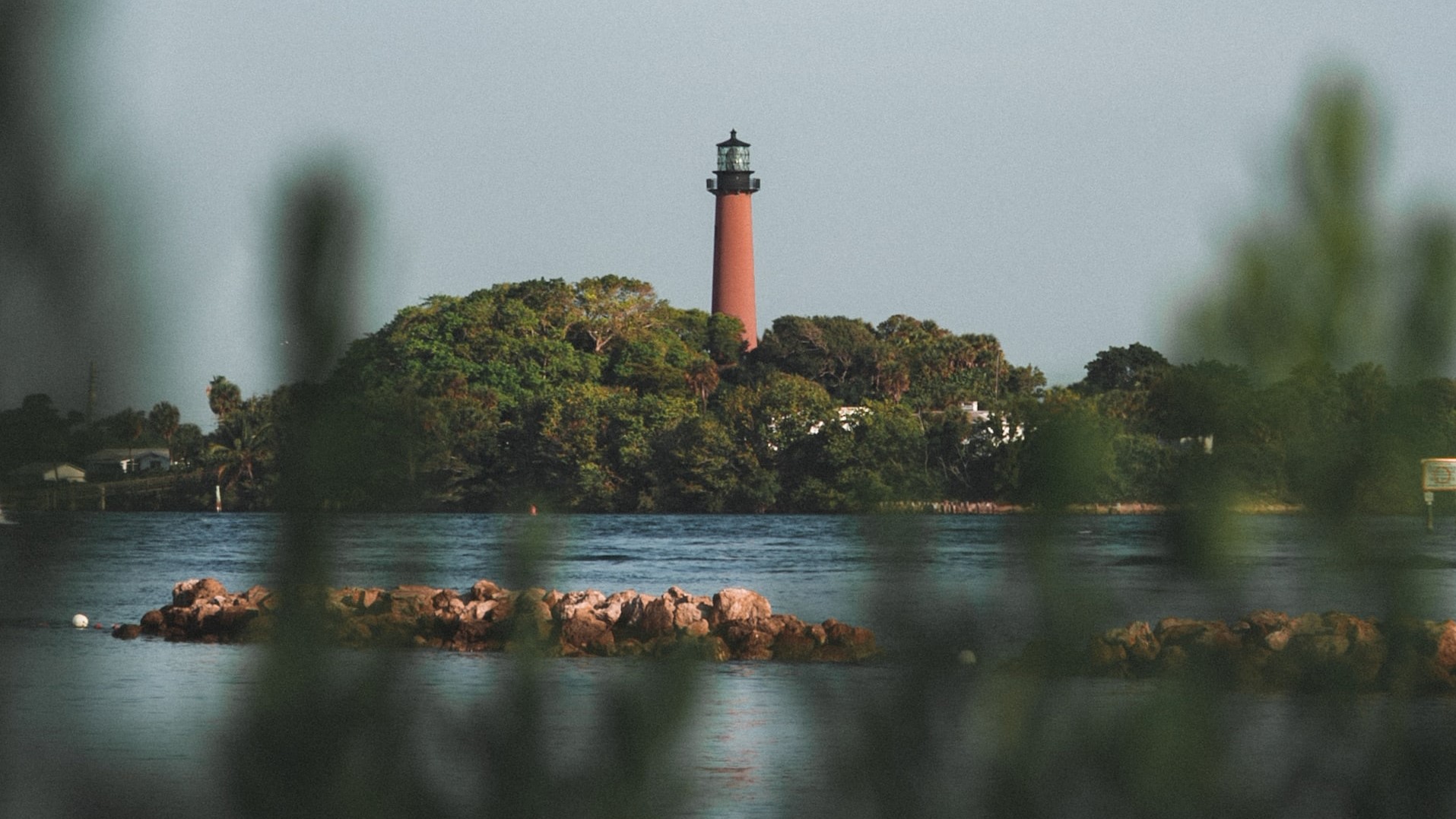 red and white lighthouse on rock formation in the middle of water | Veteran Car Donations