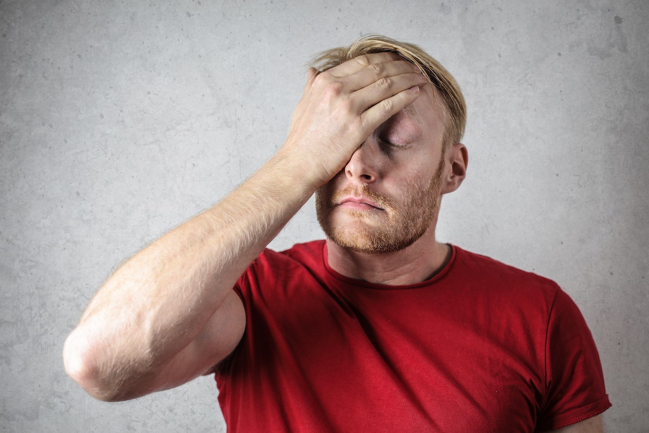 A Man in Red Shirt Covering His Face | Veteran Car Donations
