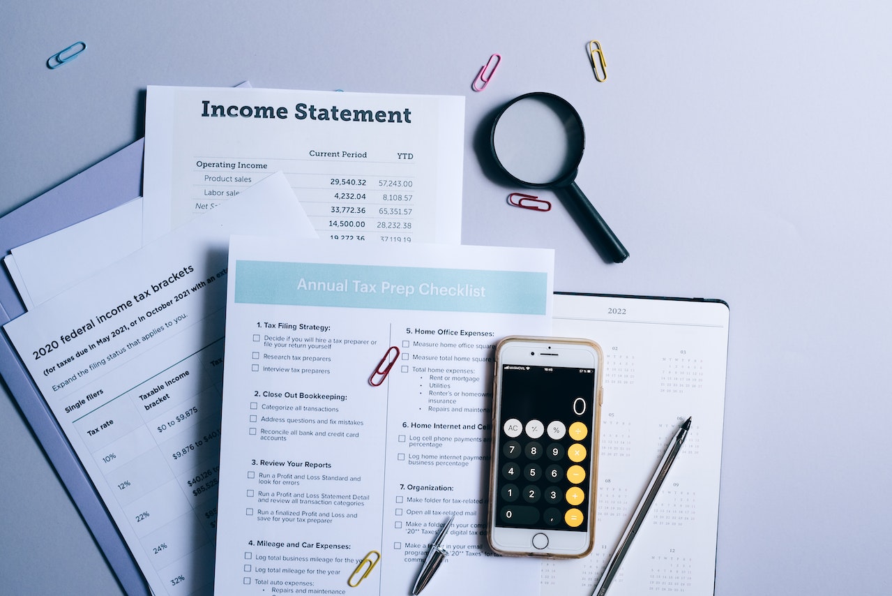 A Mobile Phone and Documents Near the Magnifying Glass on the Table | Veteran Car Donations