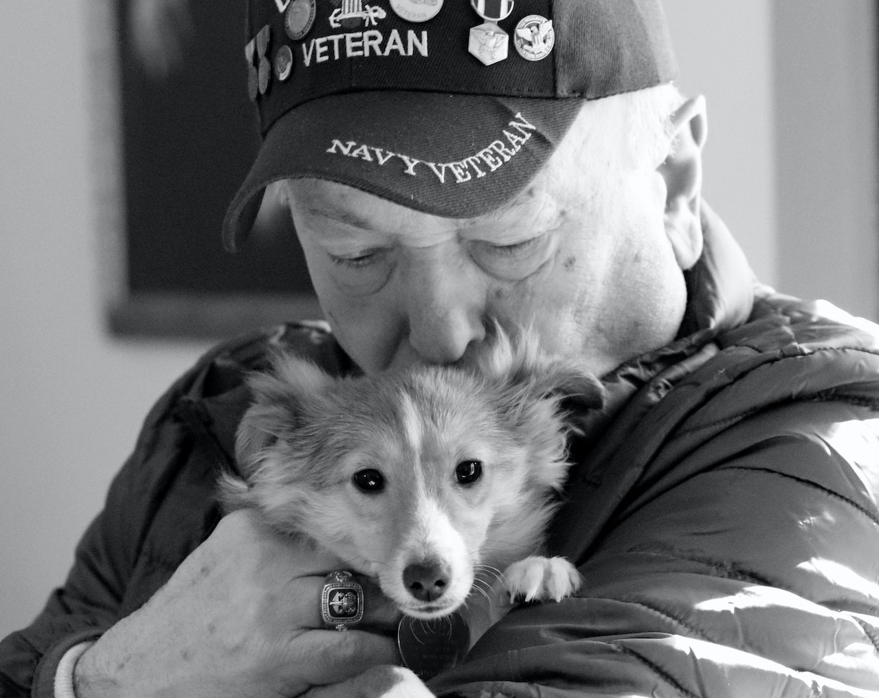 Man in Black Hat Hugging White and Brown Dog | Veteran Car Donations