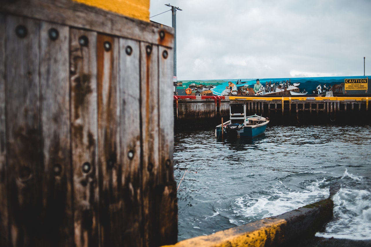 Old boat moored near weathered pier on overcast day | Veteran Car Donations
