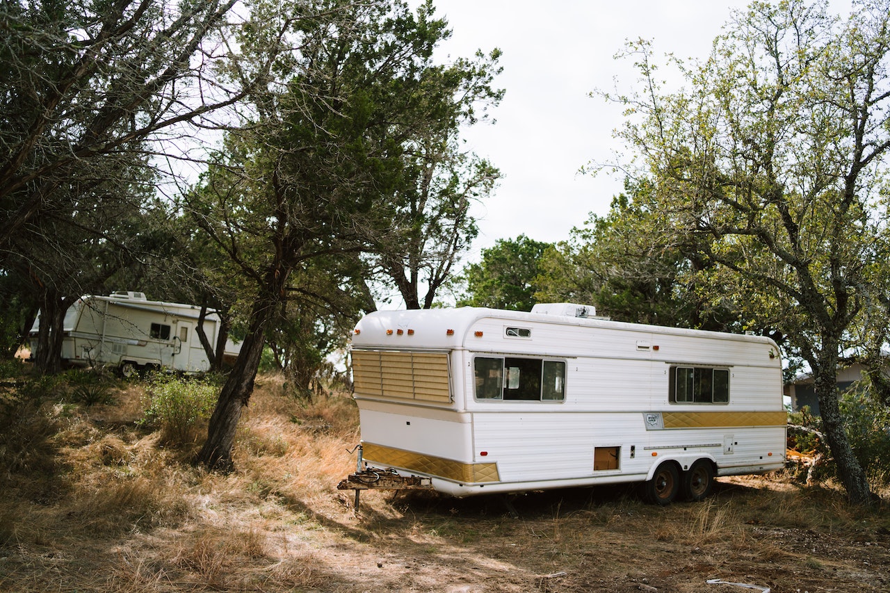 White and Brown RV Trailer Near Green Trees | Veteran Car Donations