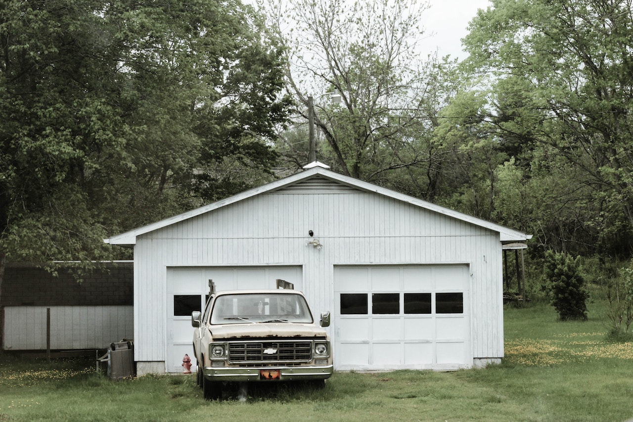 Classic White Chevrolet Pickup Truck Near White 2-door Garage Near Trees | Veteran Car Donations
