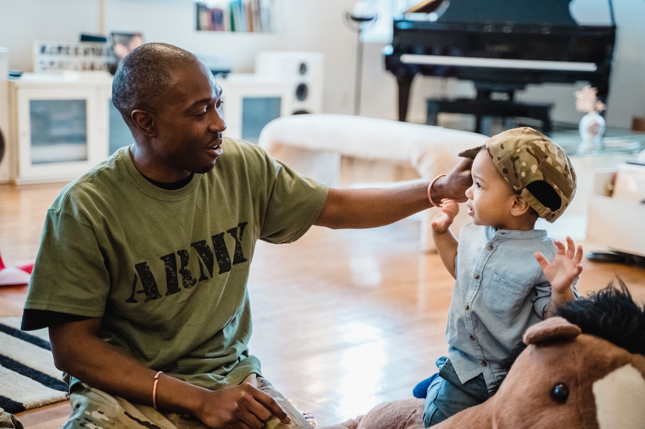 Man in Military T-Shirt Putting his Cap on His Little Son | Veteran Car Donations
