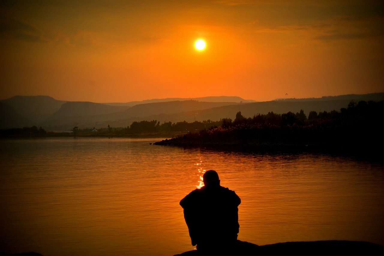 Silhouette of Person Sitting Beside Body of Water | Veteran Car Donations