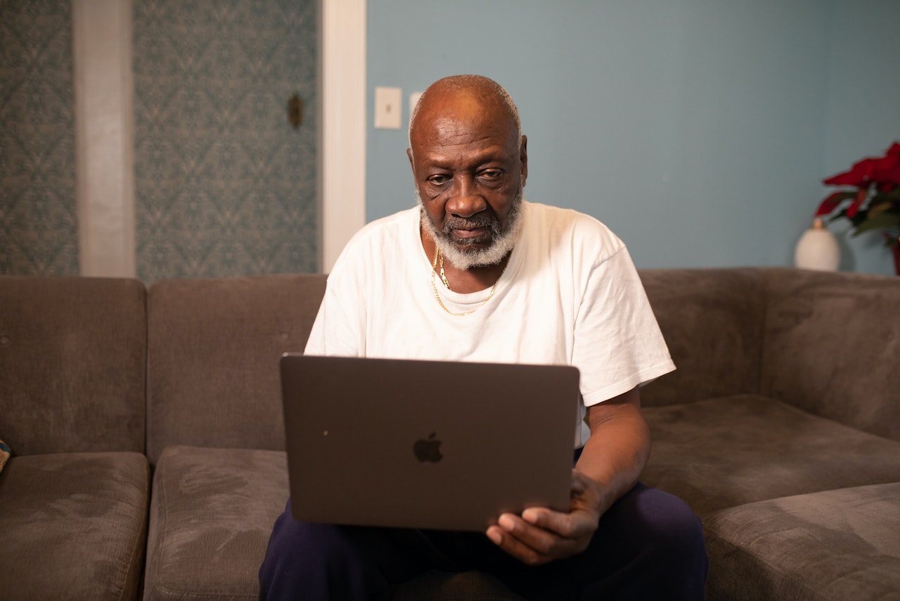Man Wearing White Crew-neck T-shirt Sitting While Using Macbook Pro | Veteran Car Donations
