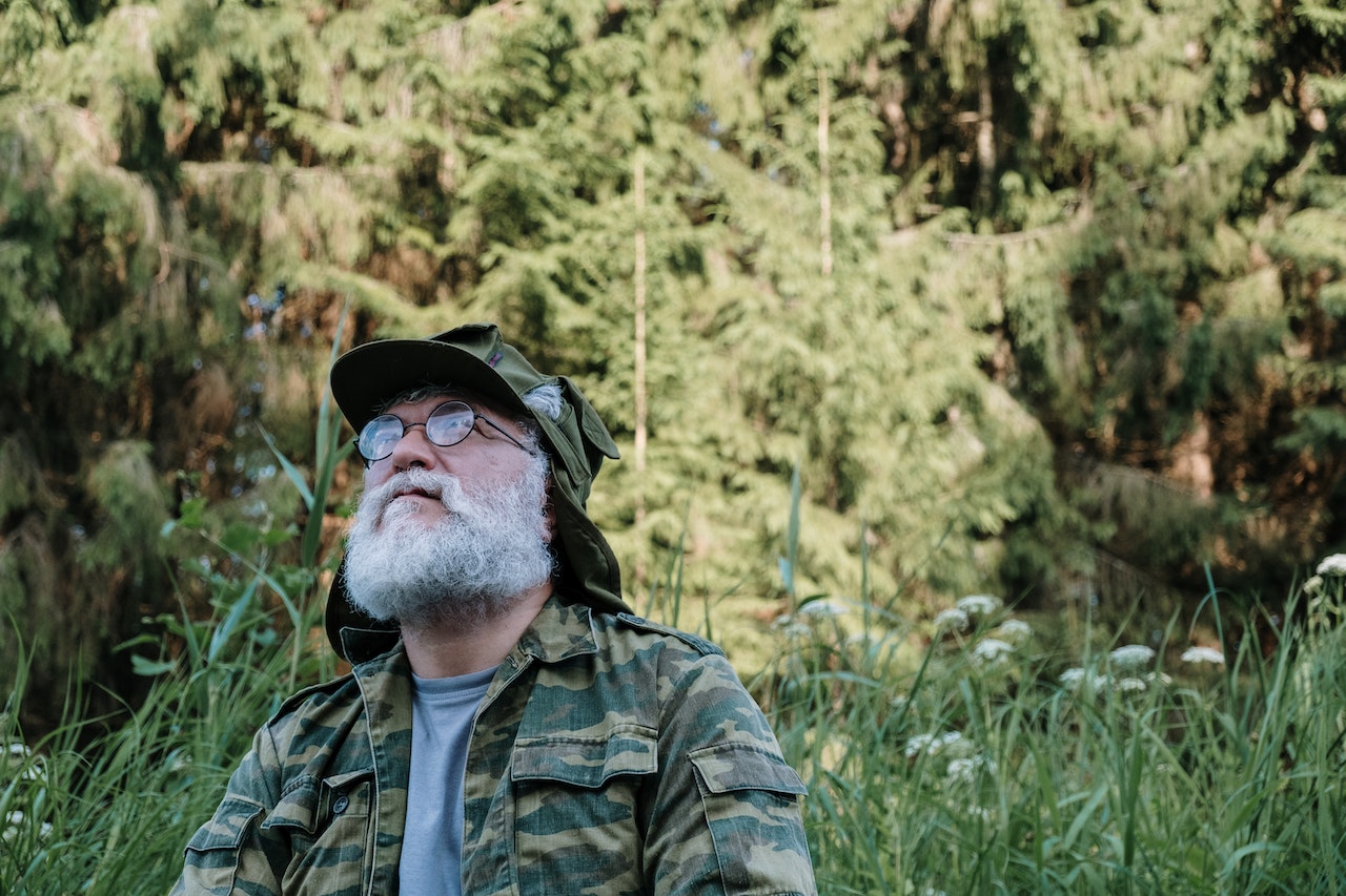 Man in Green Camouflage Jacket Standing on Green Grass Field | Veteran Car Donations
