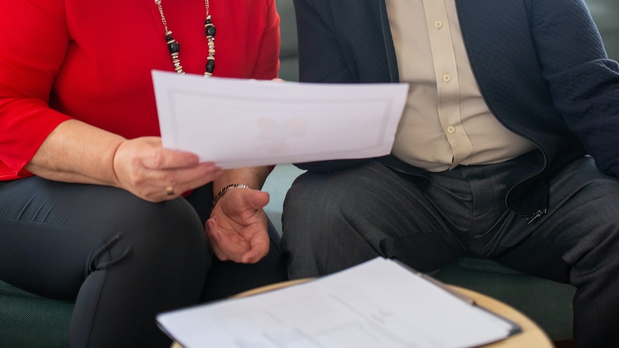 An Elderly Man and Woman Sitting on the Couch while Having Conversation | Veteran Car Donations