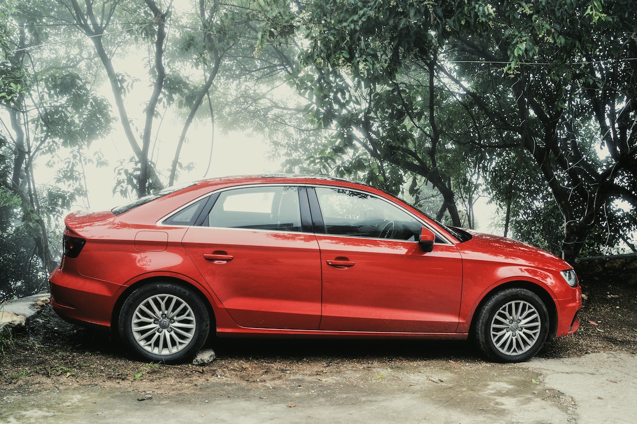 Red Sedan parked near trees | Veteran Car Donations