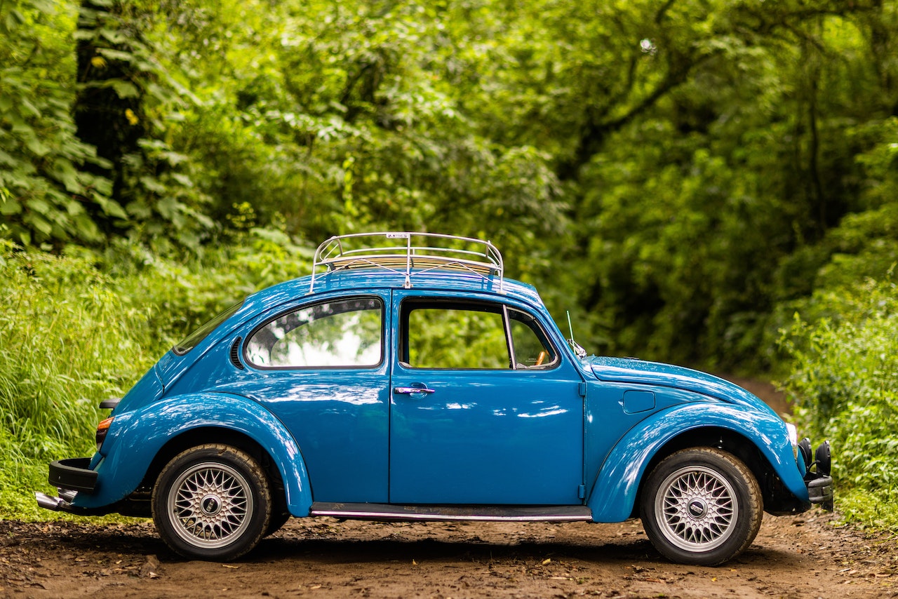 A Blue Volkswagen Beetle Parked Near Trees | Veteran Car Donations
