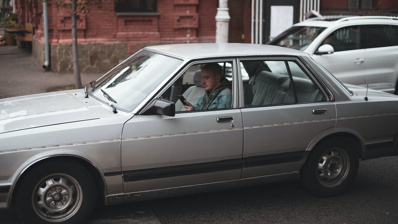 Man driving an old silver sedan | Veteran Car Donations