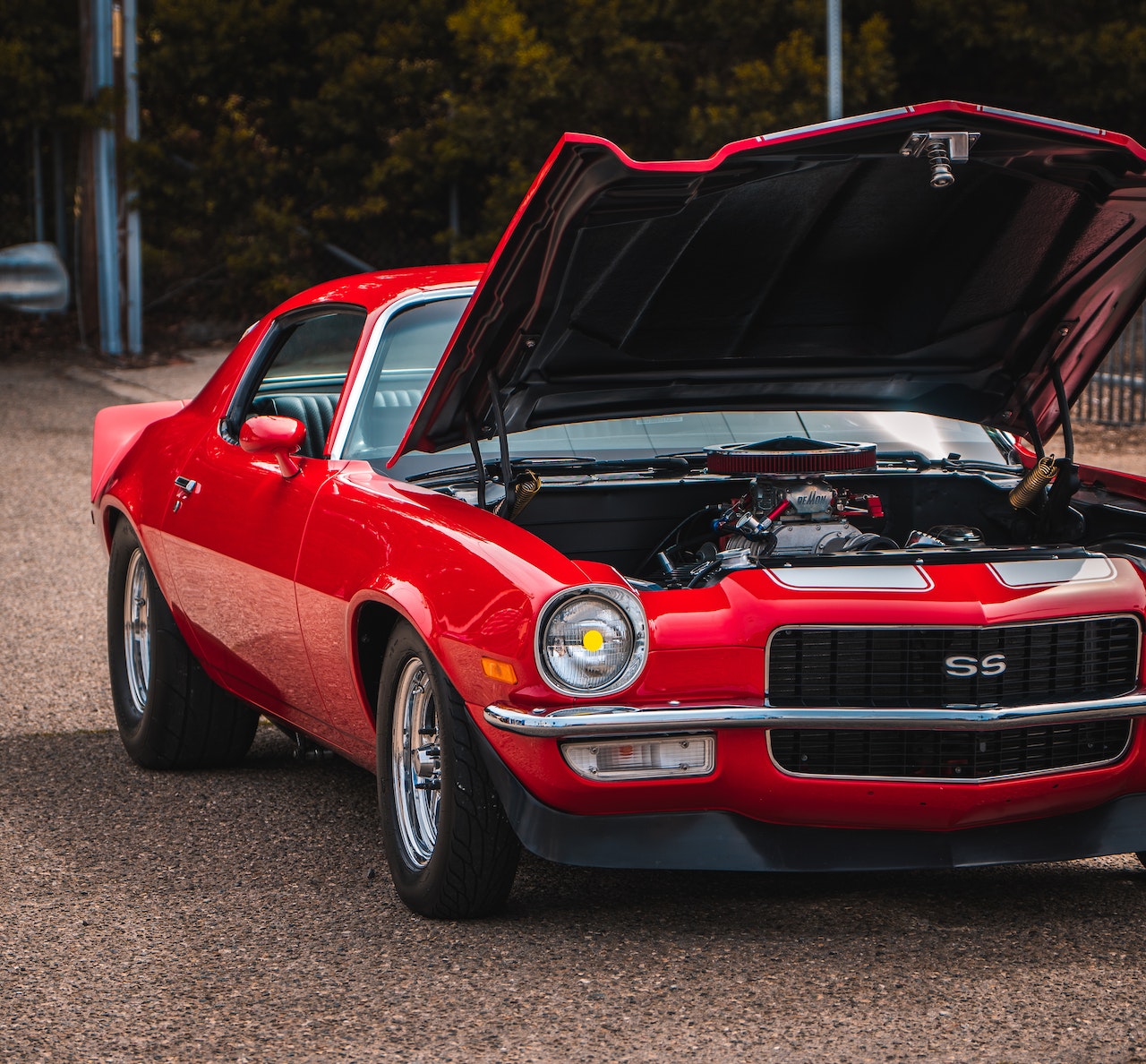 A Red Camaro Car Parked on the Street with It's Hood Open | Veteran Car Donations