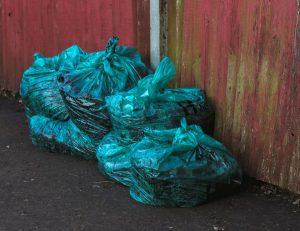 Green Plastic Bags Near a Wall | Veteran Car Donations