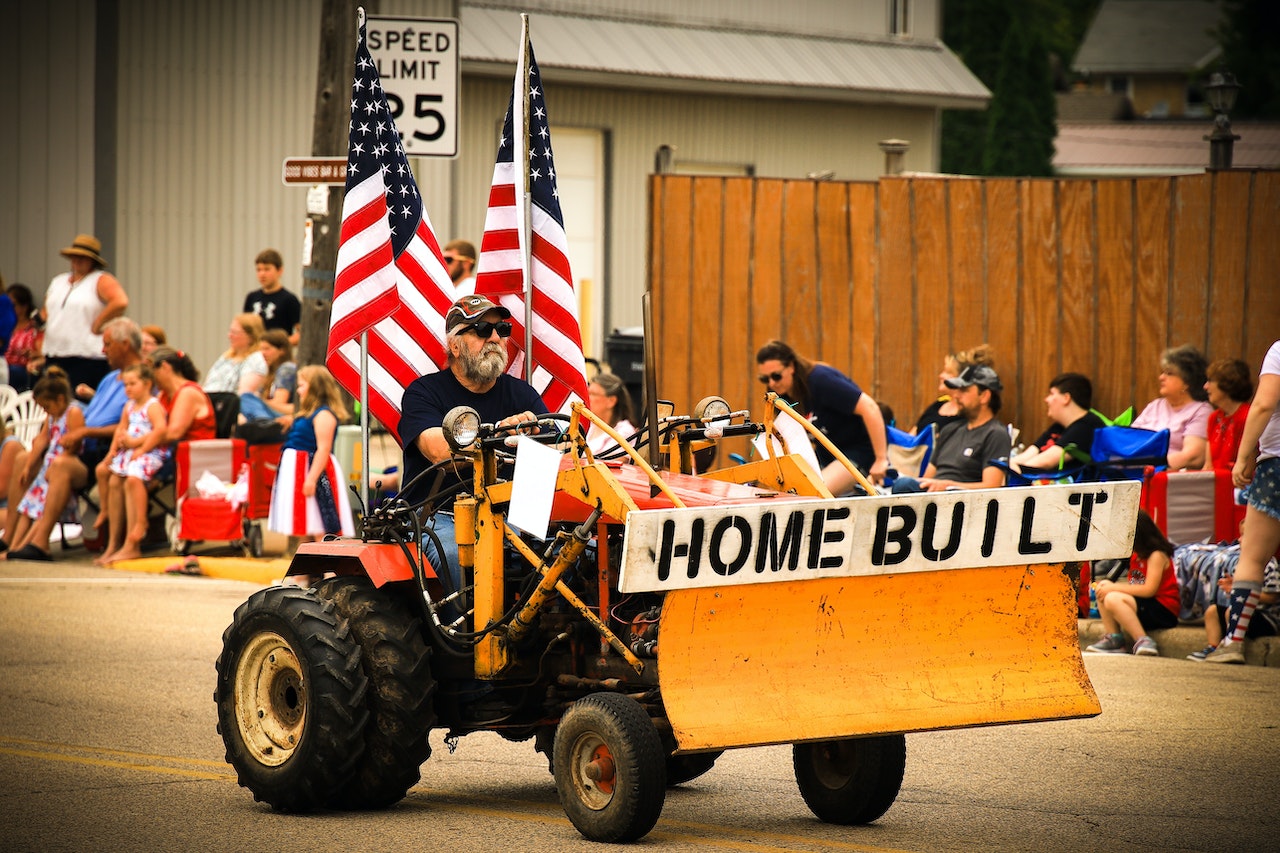 Man on a Vehicle with American Flags on a Parade | Veteran Car Donations

