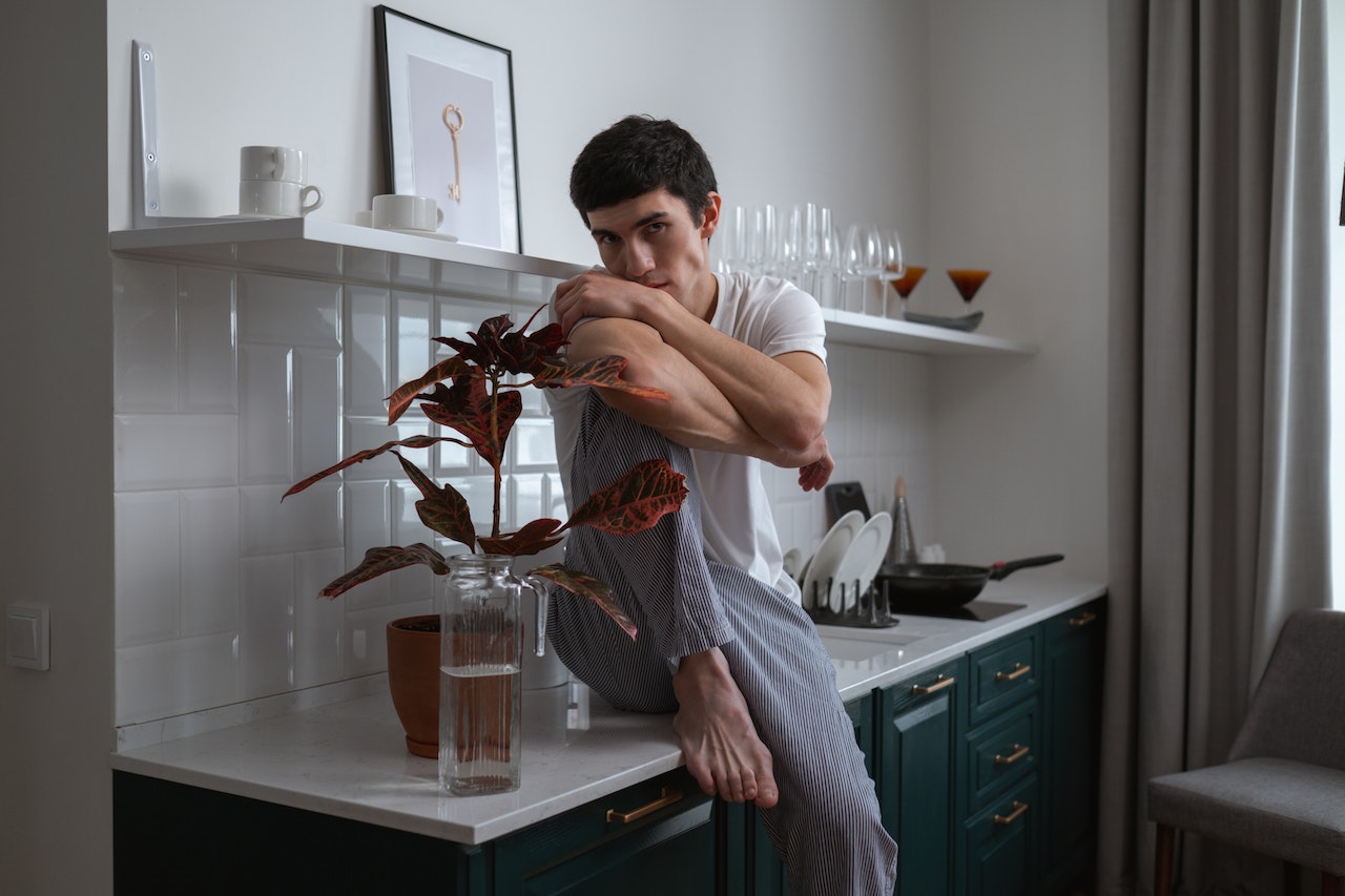 Man in White Crew Neck T-shirt Sitting on the Kitchen Counter | Veteran Car Donations
