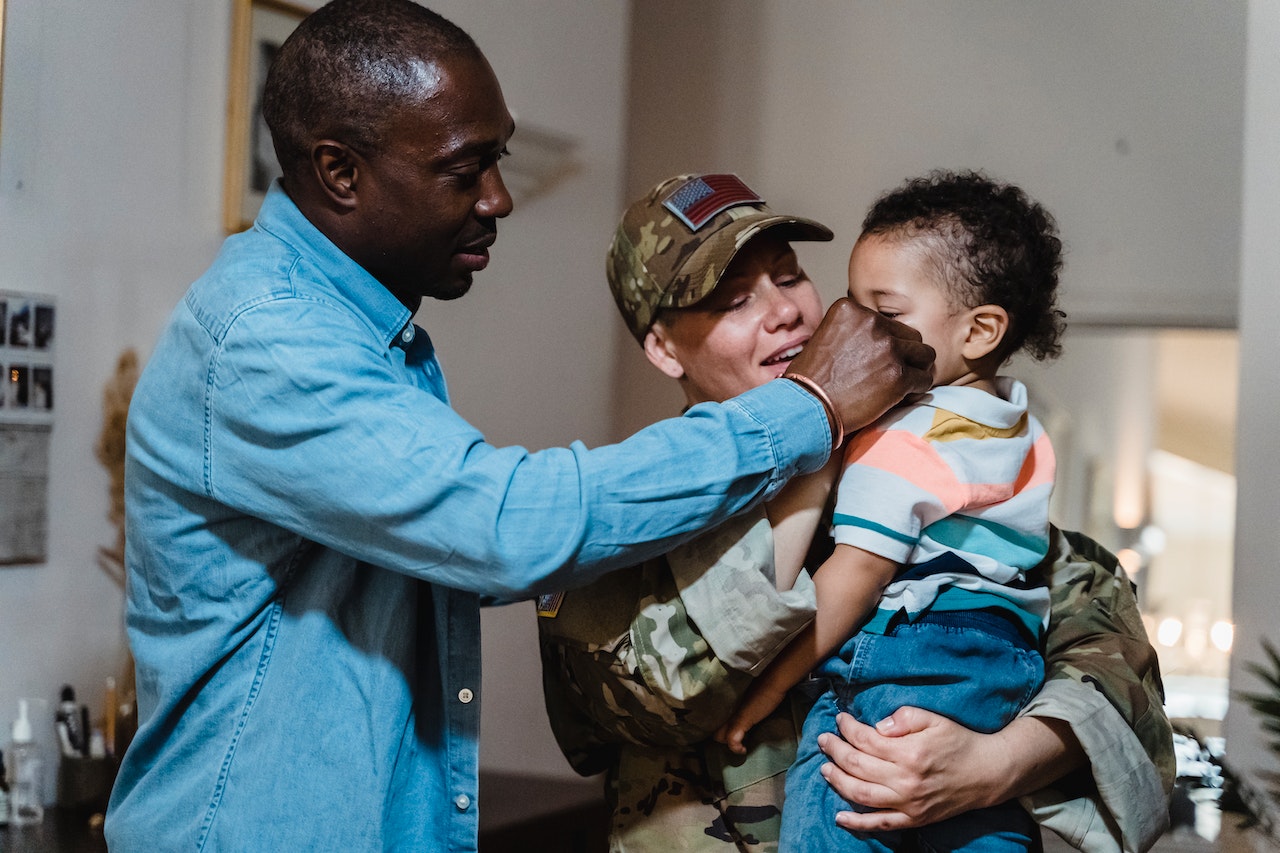 Mother in a Military Uniform Holding Her Son and the Father Standing Next to Them | Veteran Car Donations
