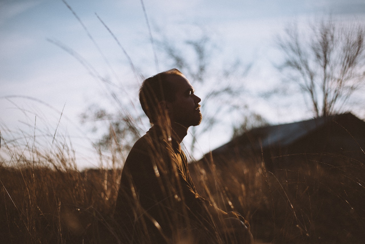 Silhouette of Man Sitting on Grass Field at Daytime | Veteran Car Donations
