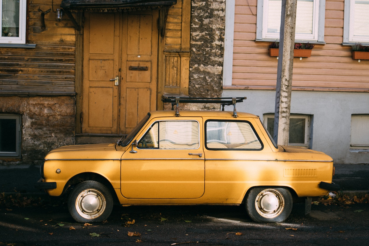 Yellow retro car parked outside old building | Veteran Car Donations

