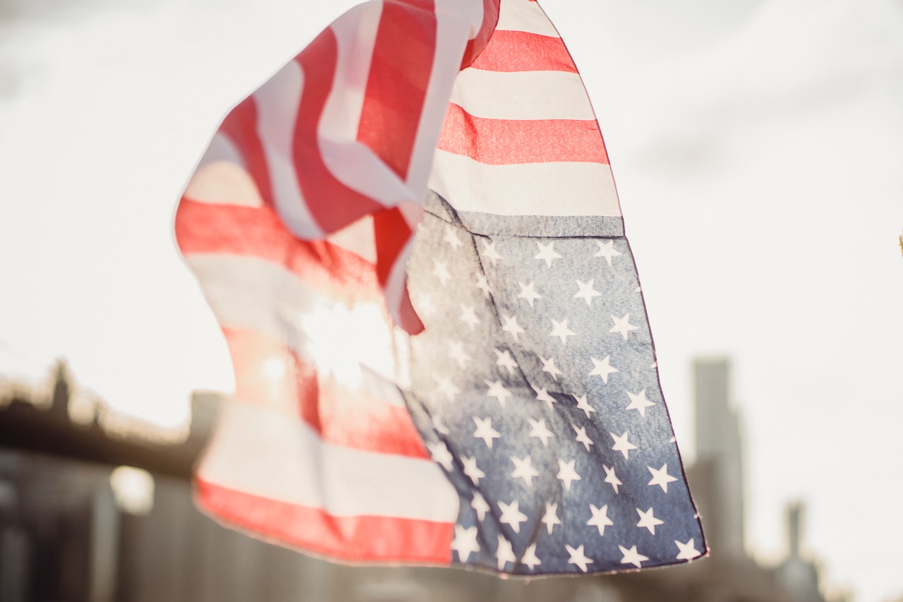 American flag kerchief waving in wind against blurred modern city | Veteran Car Donations