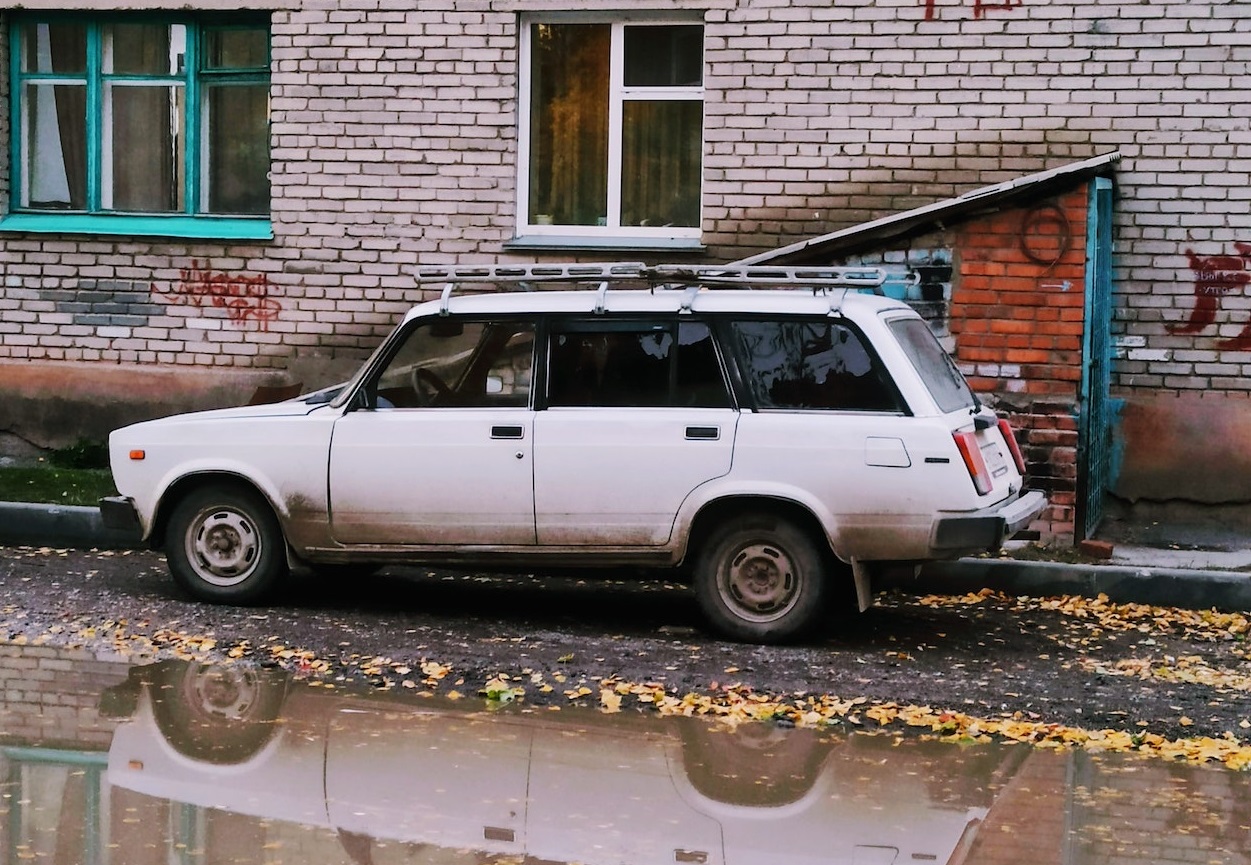 Old White SUV parked with Puddle | Veteran Car Donations