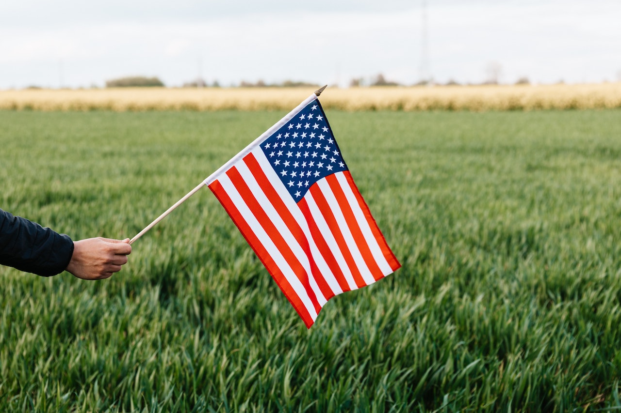 Person Showing American Flag on Field in Daytime | Veteran Car Donations
