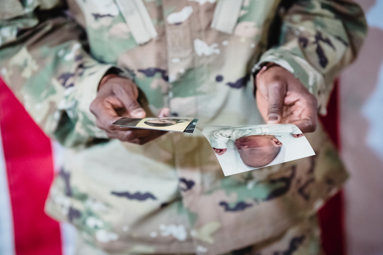 Person in Camouflage Uniform Holding Pictures | Veteran Car Donations