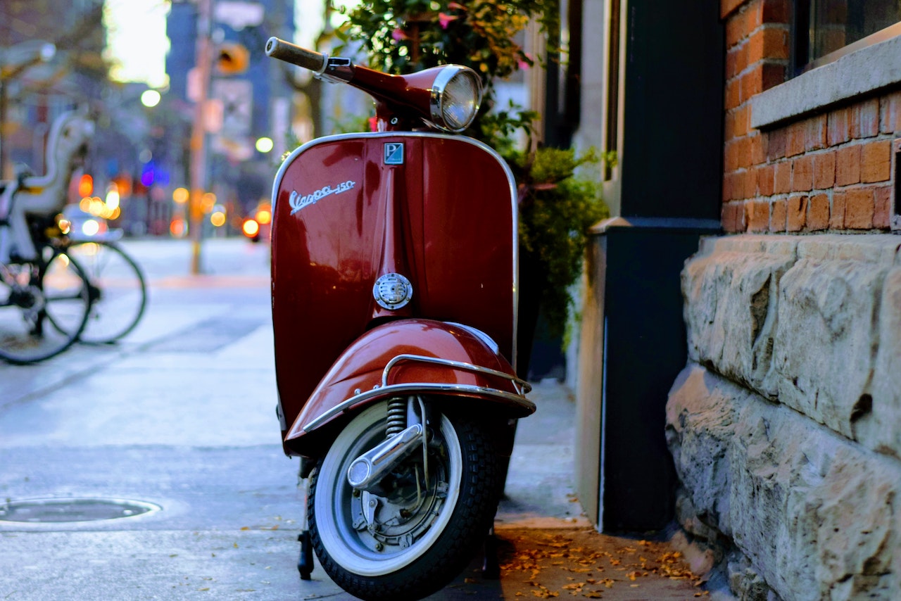 Red Vespa Parked on Sidewalk | Veteran Car Donations