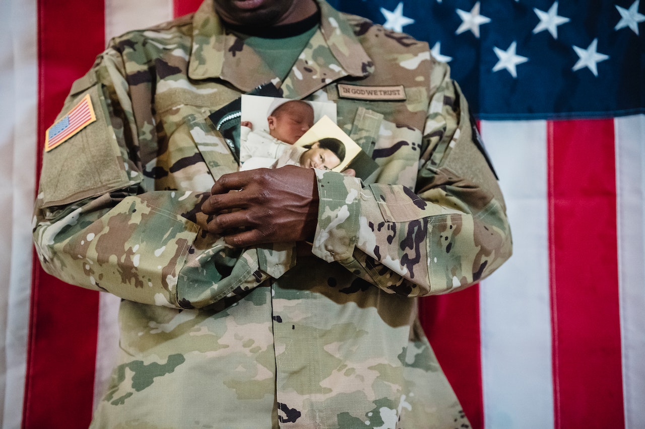 Soldier in Uniform Holding Family Photos | Veteran Car Donations