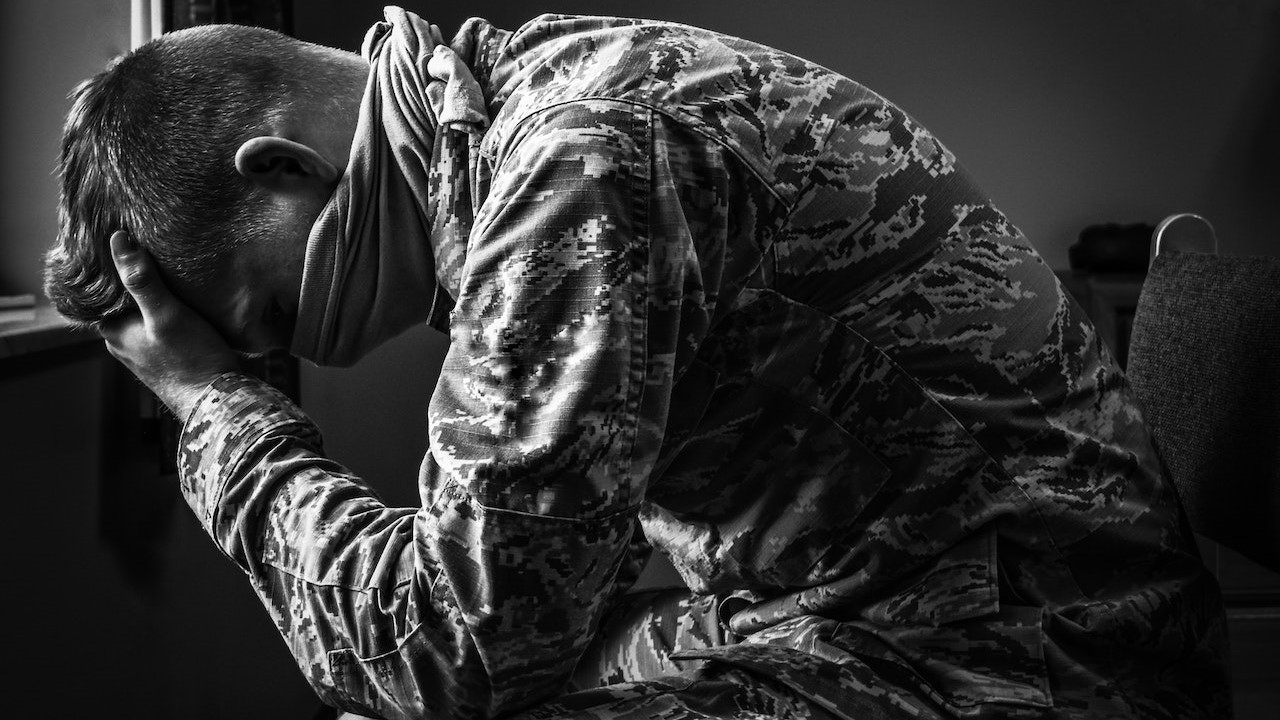 Young soldier in uniform sitting and covering face with hand | Veteran Car Donations
