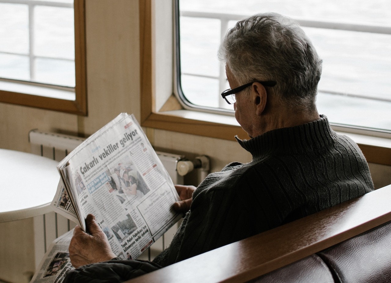 Man Sitting on Bench While Reading Newspaper | Veteran Car Donations