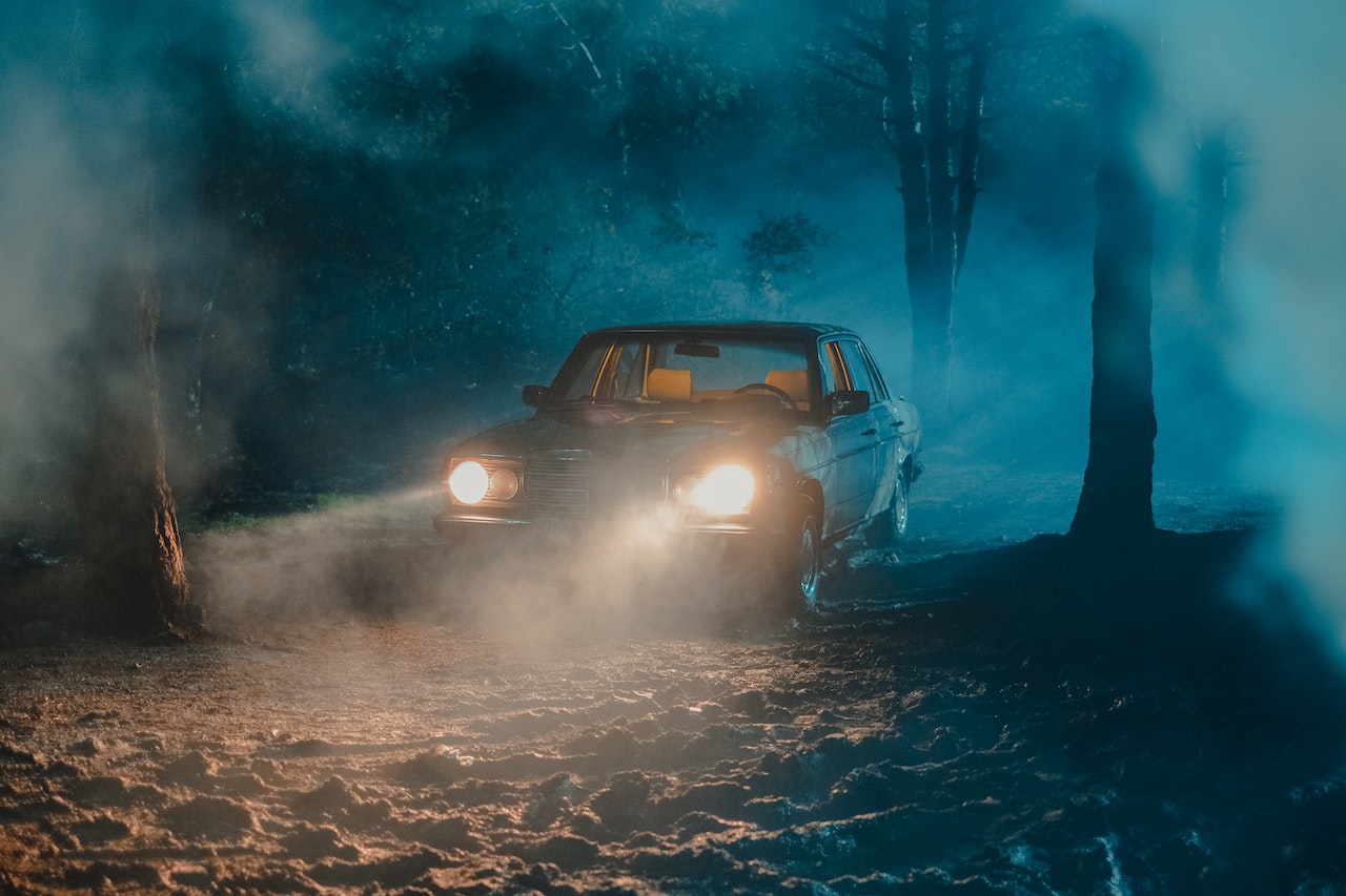 Old fashioned car with luminous headlights in dark forest | Veteran Car Donations