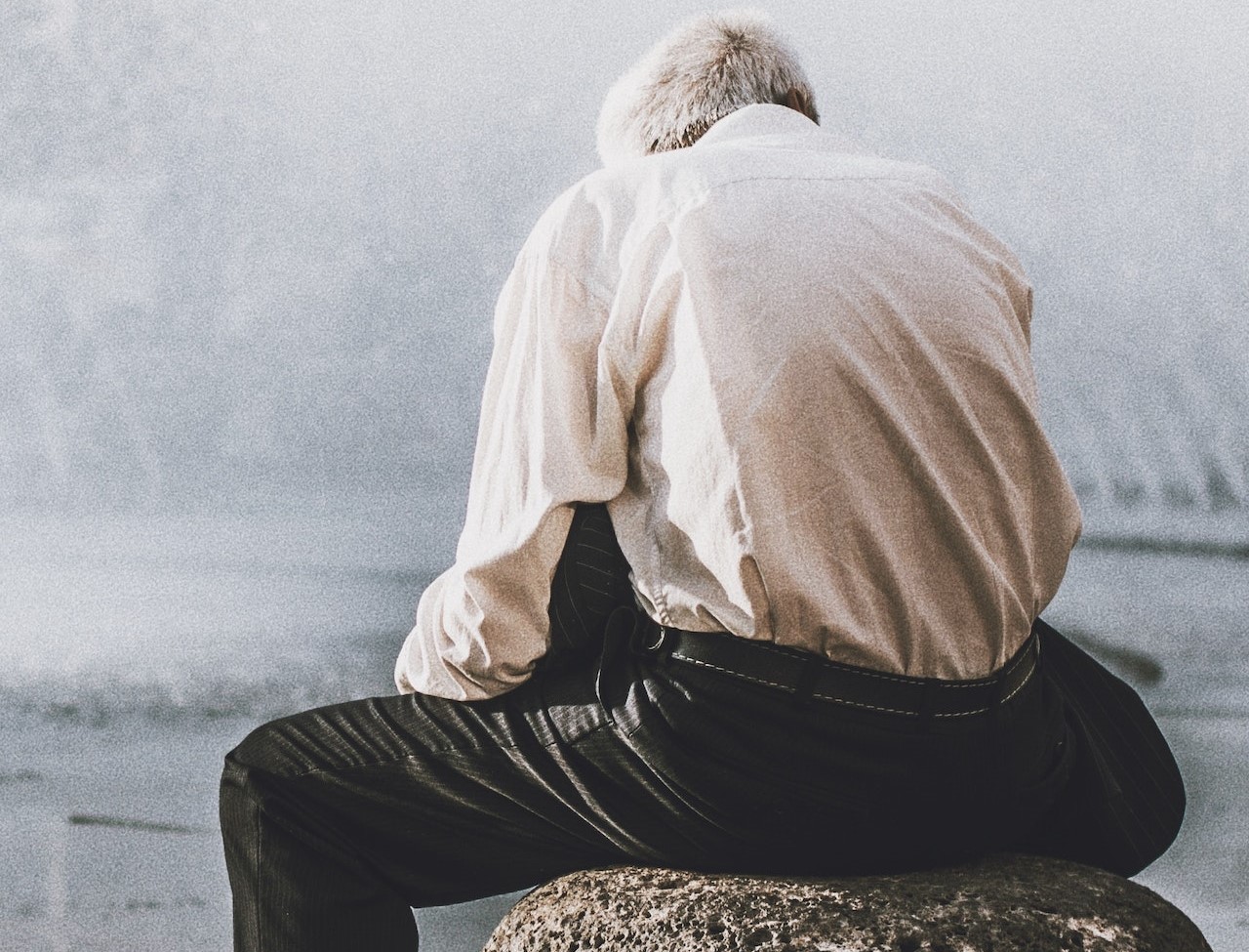 Man Sitting on Rock in Front of Water Fountain | Veteran Car Donations
