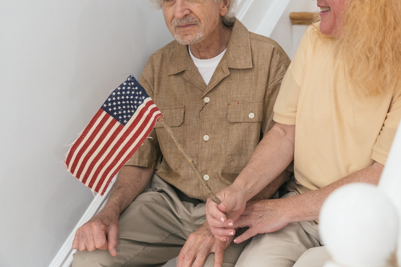 A Couple Sitting on the Steps with a Flag | Veteran Car Donations