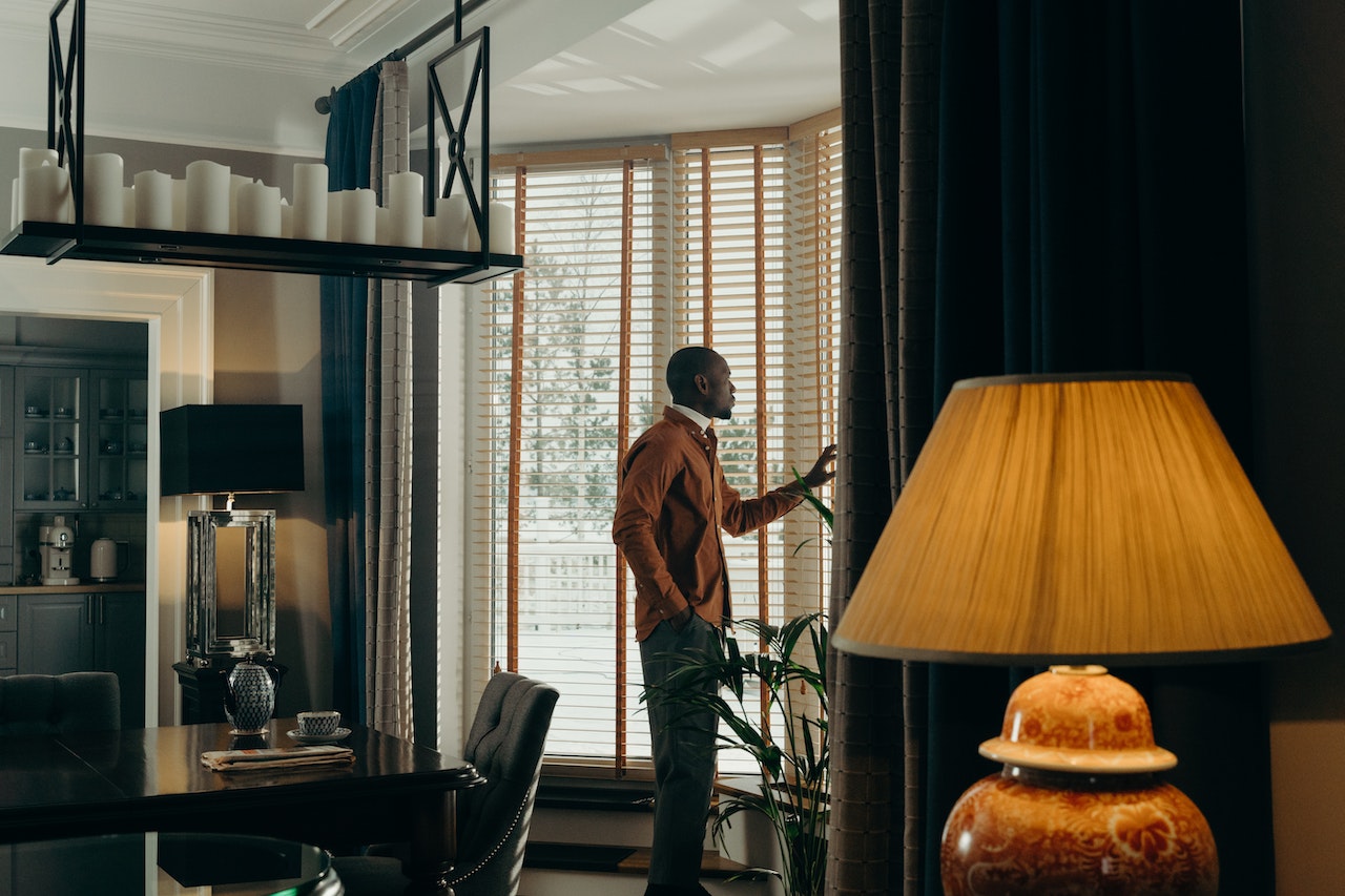 Man Standing Near the Window with Wooden Blinds | Veteran Car Donations