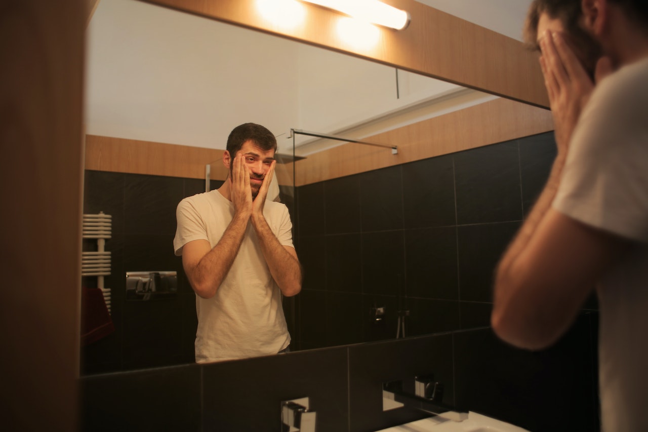 Tired man looking in mirror in bathroom | Veteran Car Donations