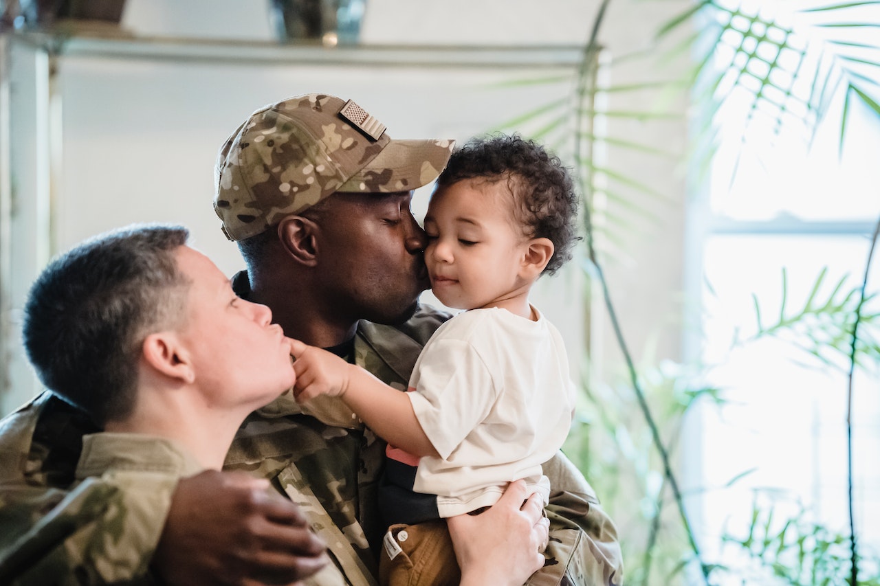 A Man in Military Uniform Kissing his Child | Veteran Car Donations
