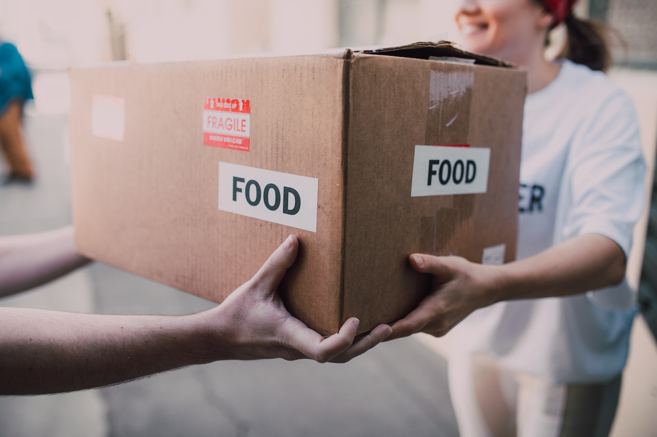 People Handing Over a Brown Box | Veteran Car Donations
