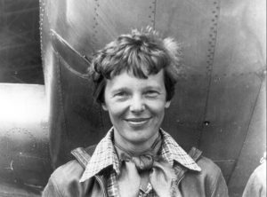 Amelia Earhart standing under nose of her Lockheed Model 10-E Electra | Veteran Car Donations