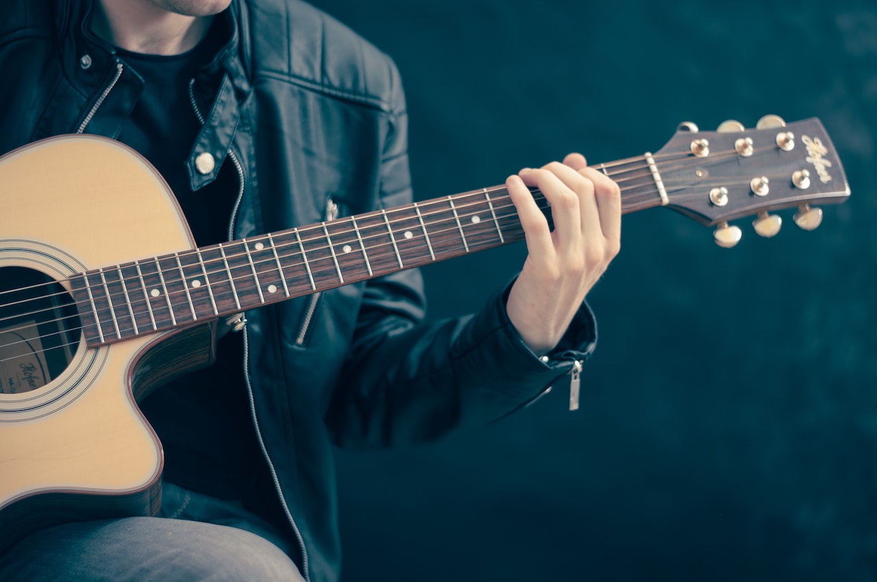 Person Holding Brown and Black Guitar | Veteran Car Donations