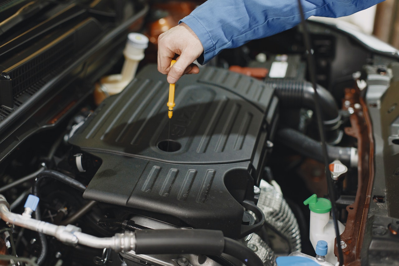 Person Checking the Oil of an Engine | Veteran Car Donations
