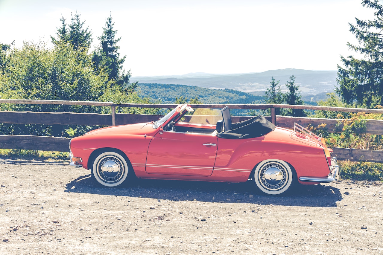 Red Convertible Coupe Parked Near Wooden Fence | Veteran Car Donations
