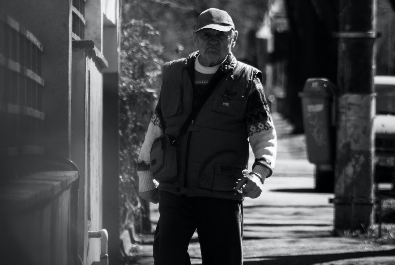 Grayscale Photo of an Elderly Man Walking on Sidewalk | Veteran Car Donations
