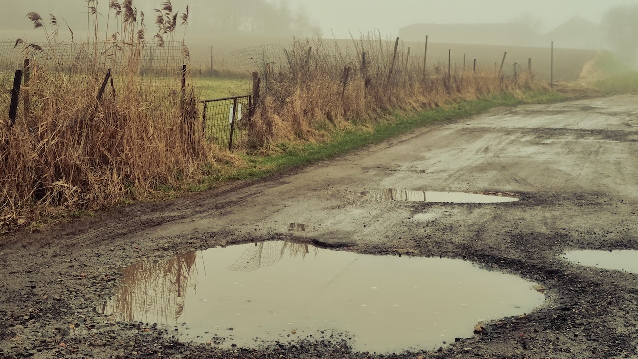 Potholes with Water on Dirt Road | Veteran Car Donations