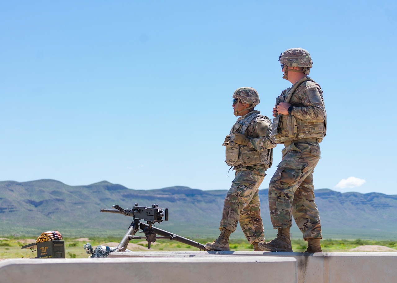 Man in Camouflage Uniform Standing Near an Automatic Weapon | Veteran Car Donations
