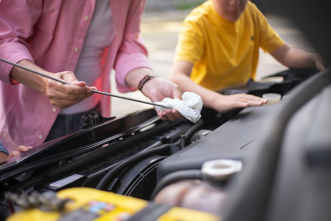 A Man Checking the Oil of a Car Engine | Veteran Car Donations
