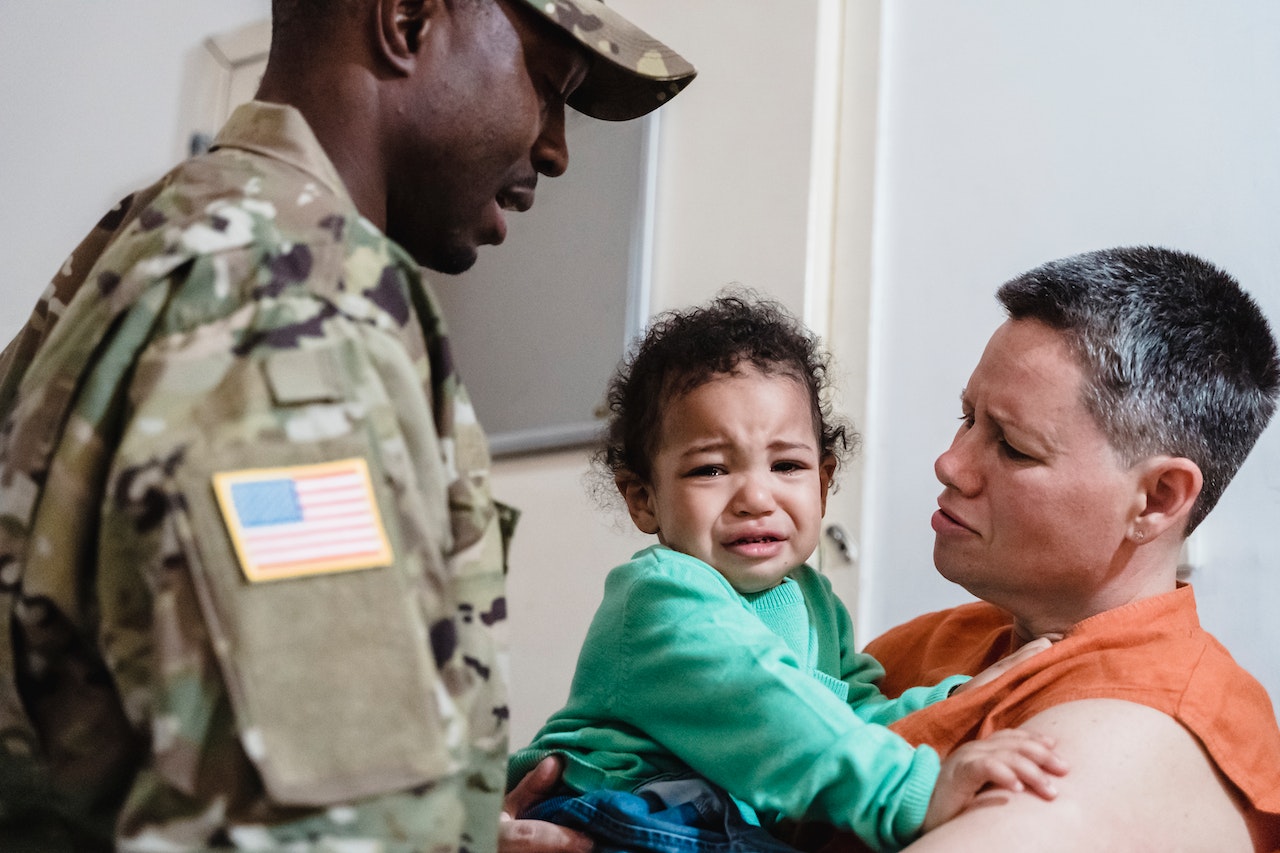 Man Standing by a Woman Holding Their Crying Son | Veteran Car Donations
